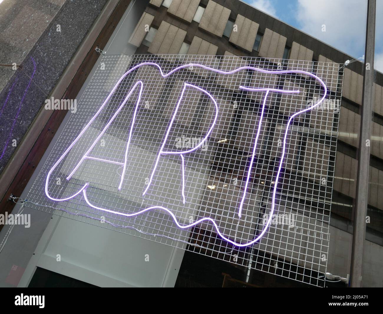 Art neon sign in a window with reflection of surrounding streetscape. Stock Photo