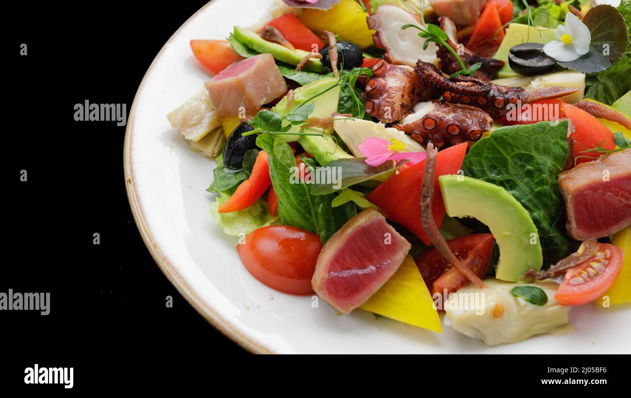 Salad with octopus, tuna and vegetables, on a dark background Stock Photo