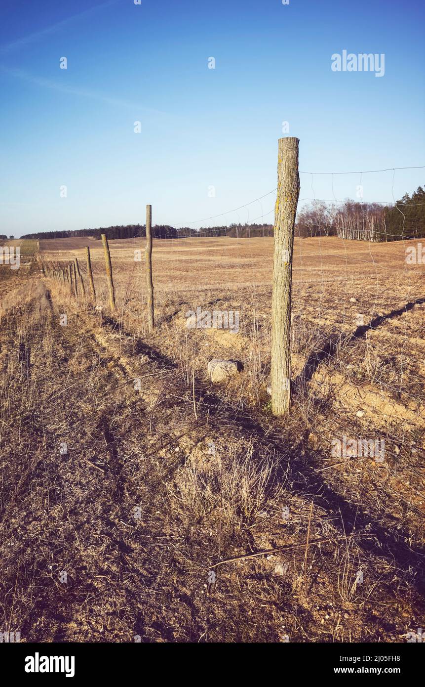 Agricultural field with wire fence, color toning applied. Stock Photo