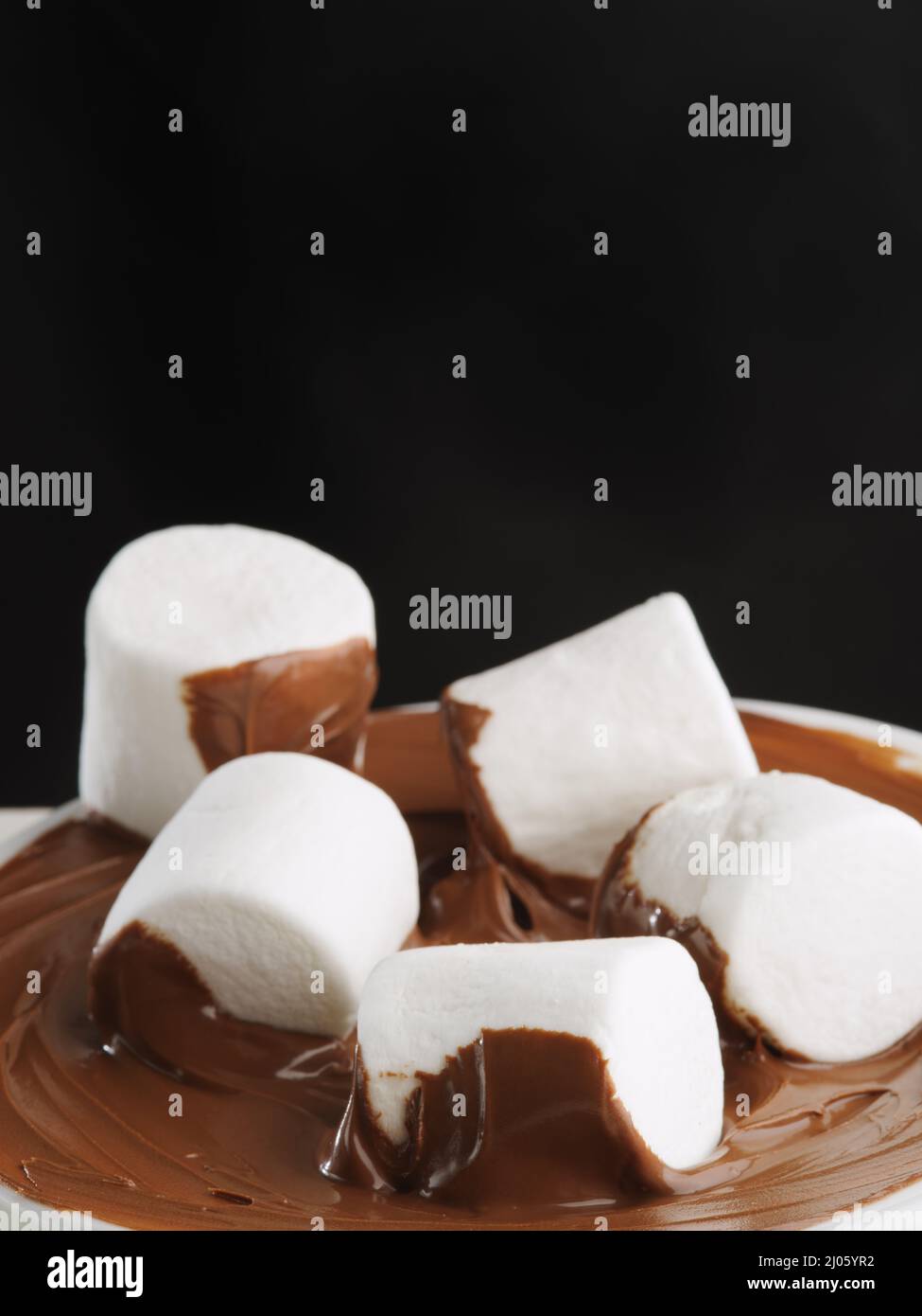 White marshmallows in chocolate paste on a black background. Birthday