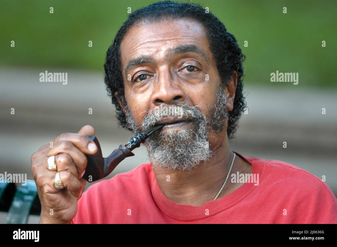 Senior ETHNIC BLACK man with full face with short hair smoking pipe and talking Stock Photo