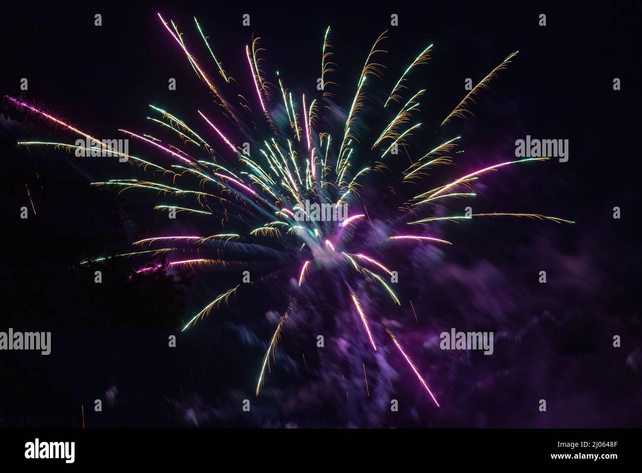 purple and green sparks from small firework explosion for new years ...