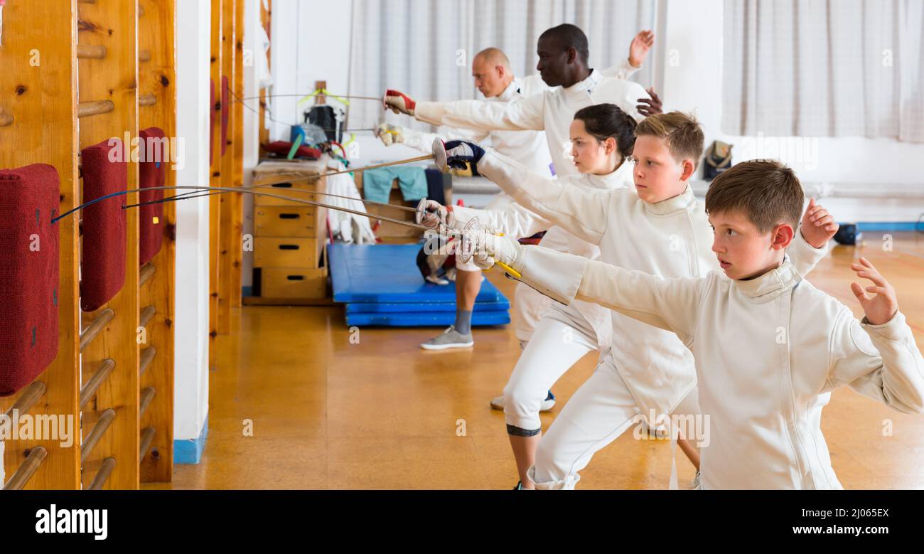 Happy mixed age group of athletes at fencing workout, training attack