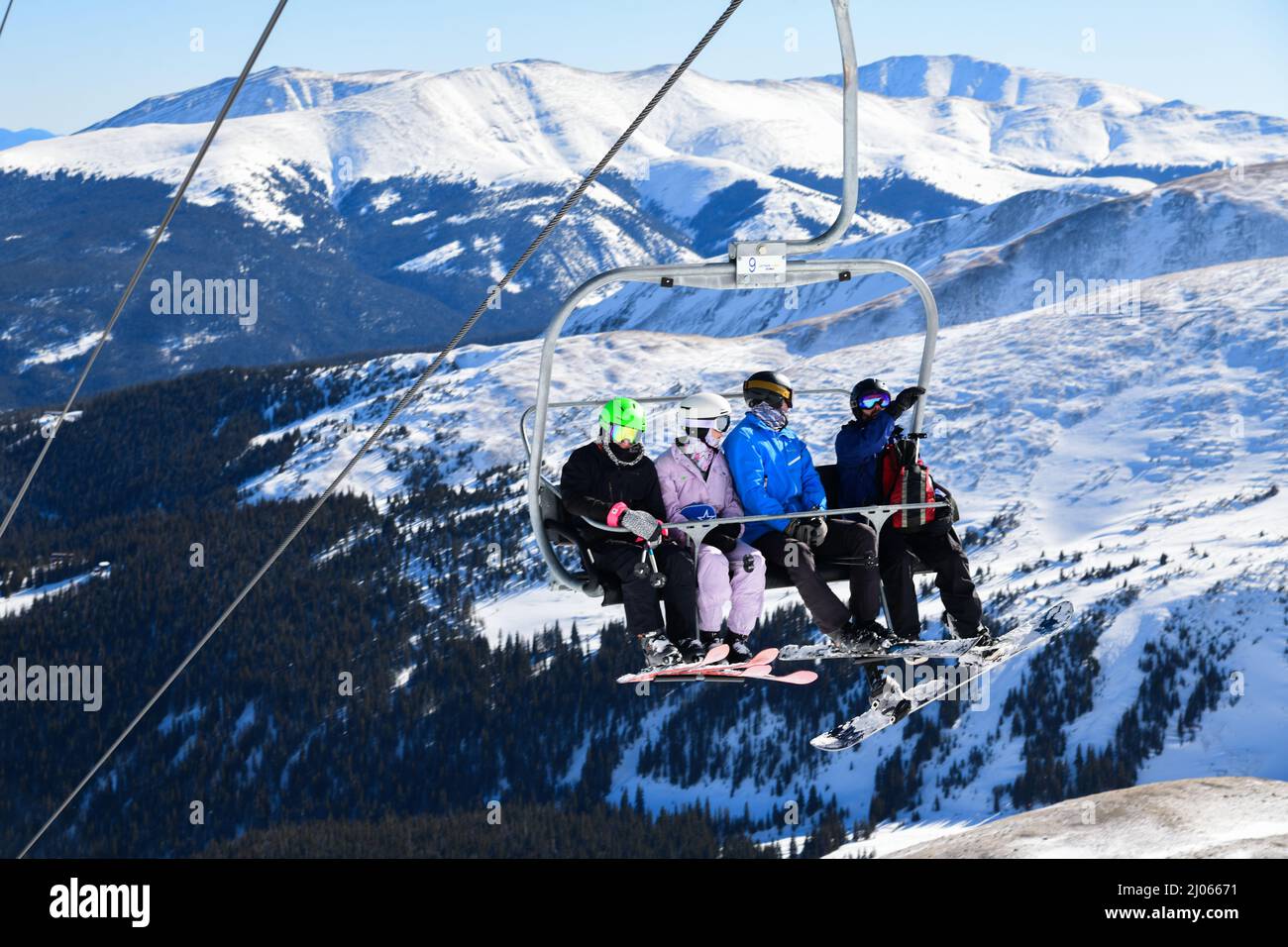 Skiers and snowboarders riding chair lift at Breckenridge Ski Resort ...
