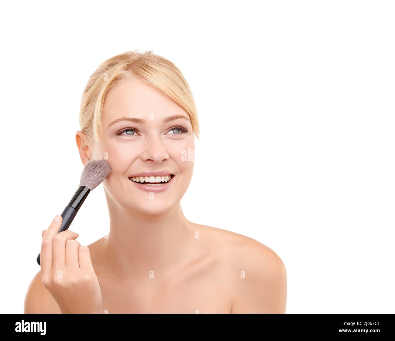 Youre making me blush. A young woman applying make-up to her face isolated on white. Stock Photo