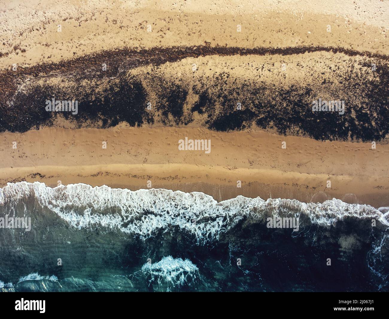 Aerial top view of a beach with a blue colored sea, yellow sand and ...