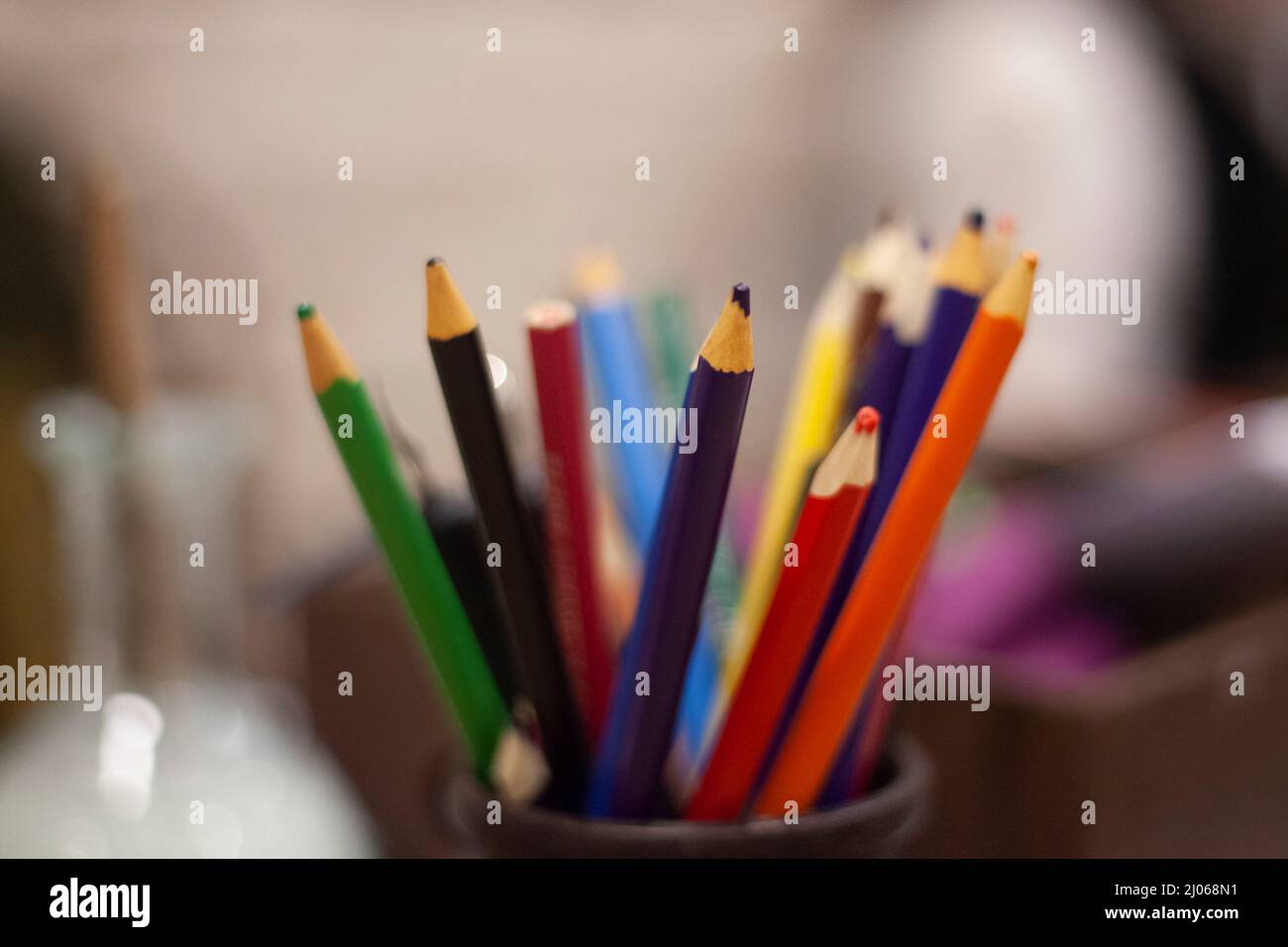 Pencils of different colors. Drawing kit. Purple and red acrylic pencil stands in jar. Background details of artist's work. Stock Photo