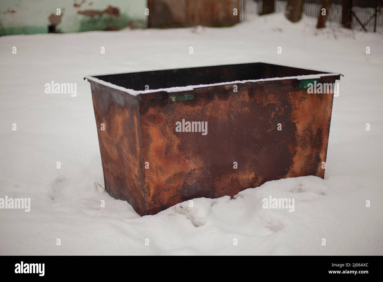 Rusty container stands in snow. Garbage can outside. Garbage in Russia. Old waste collection tank. Stock Photo