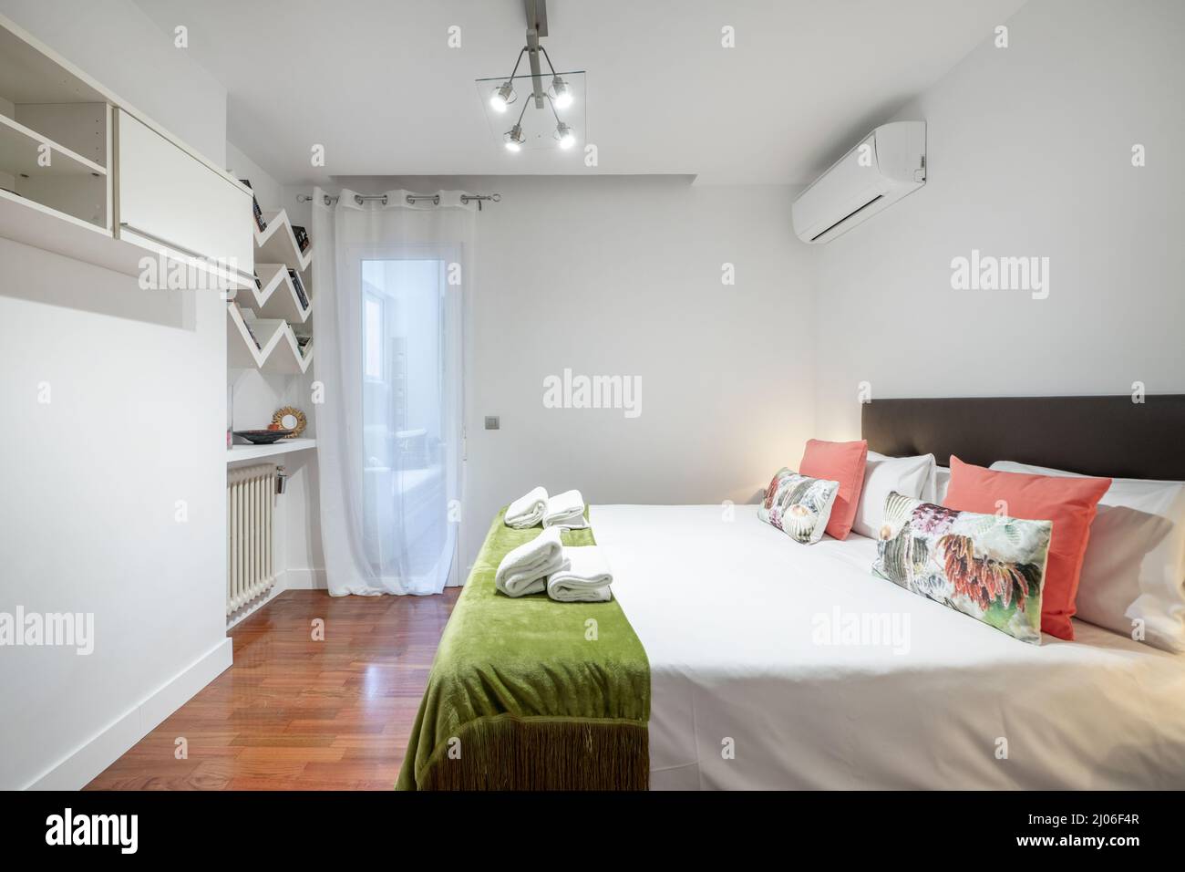 Bedroom with king size bed, shelves, cast iron radiator with cushions