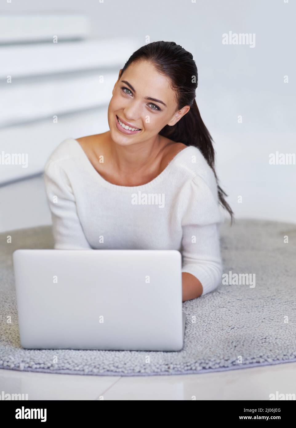 Instant access to information. A beautiful young woman lying on her floor at home and using a laptop. Stock Photo