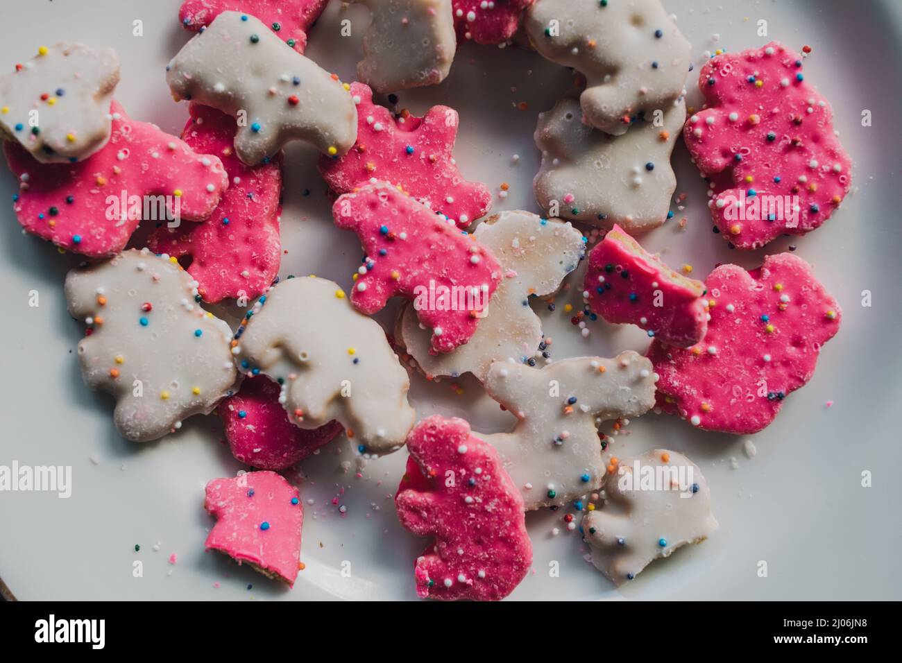 frosted Circus Animal Cookie Pink and White Sprinkled Animal Crackers on white plate Stock Photo