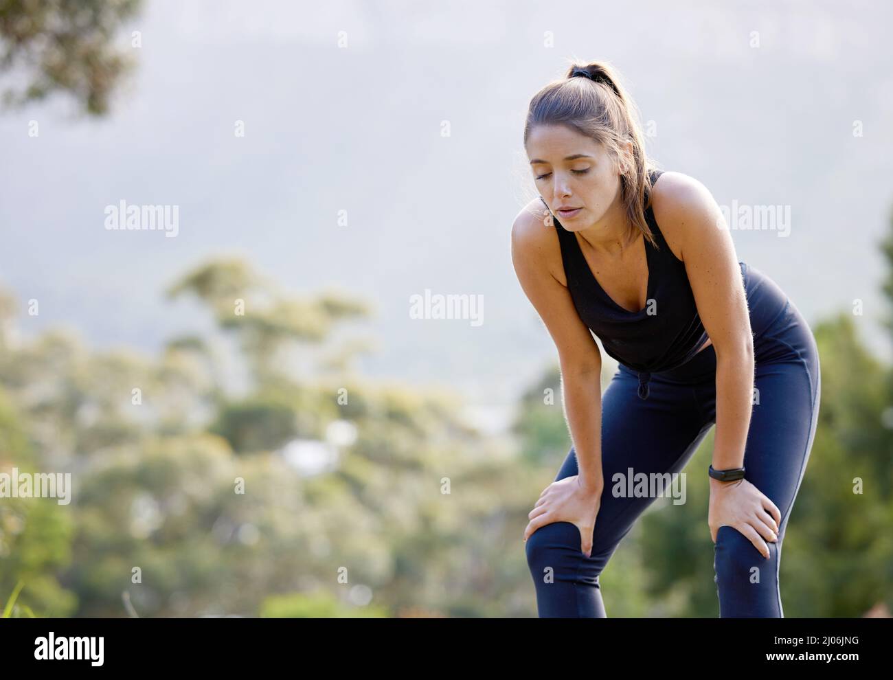 Some days will be more challenging than others. Shot of a sporty young woman catching her breath while exercising outdoors. Stock Photo