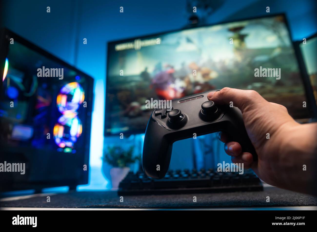 A gamer plays a video game on a big screen TV with a joystick in his hand. Online  games with friends, win prizes. Fun entertainment. Back view. Neon l Stock  Photo -