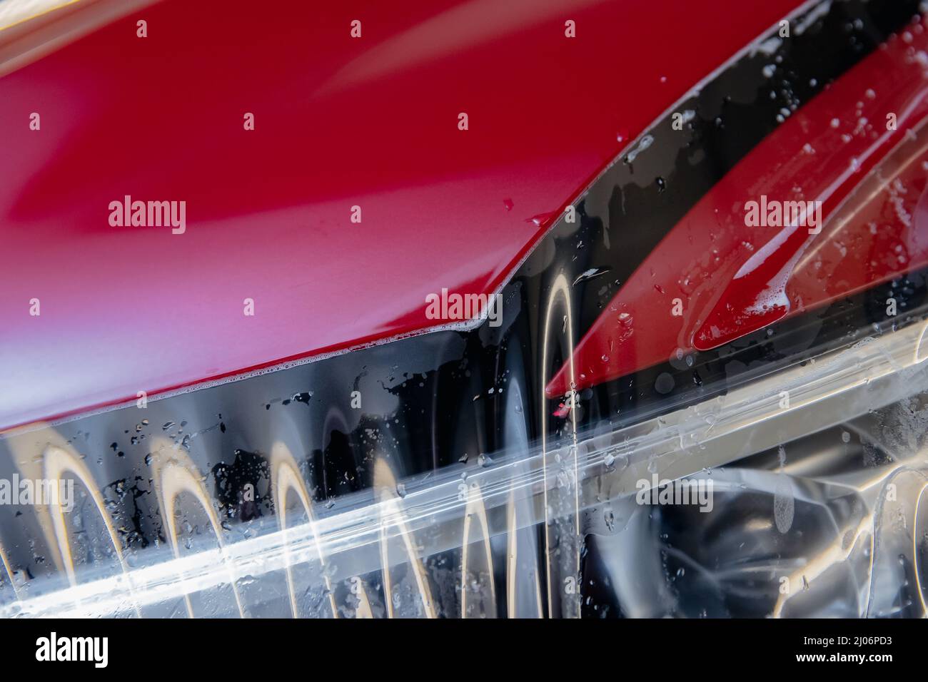 Process of pasting hood of red car with protective vinyl film from