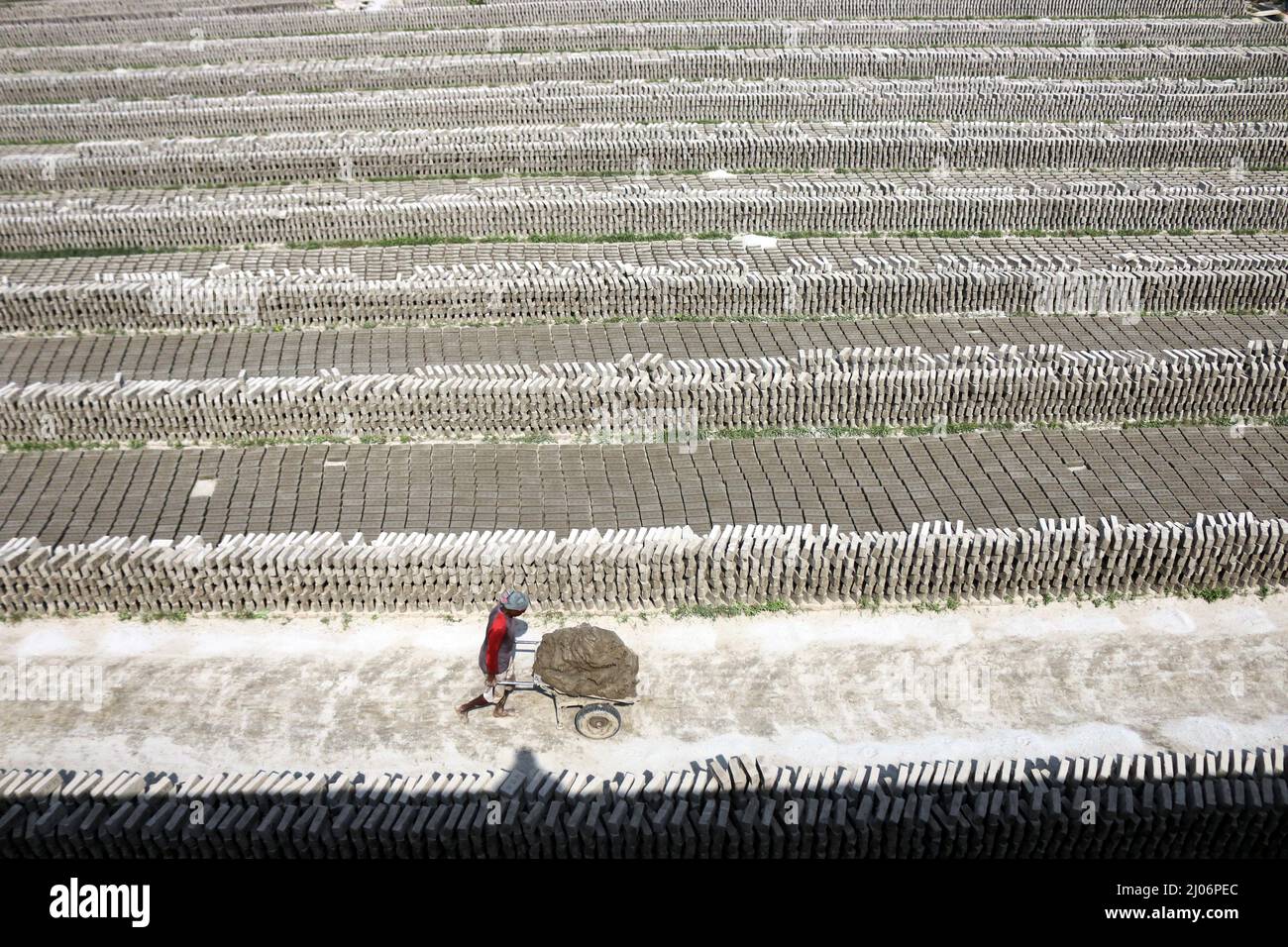 Workers transport bricks on their heads at a brick factory. Due to the high demand for bricks due to the accelerated urbanization in Bangladesh, the b Stock Photo