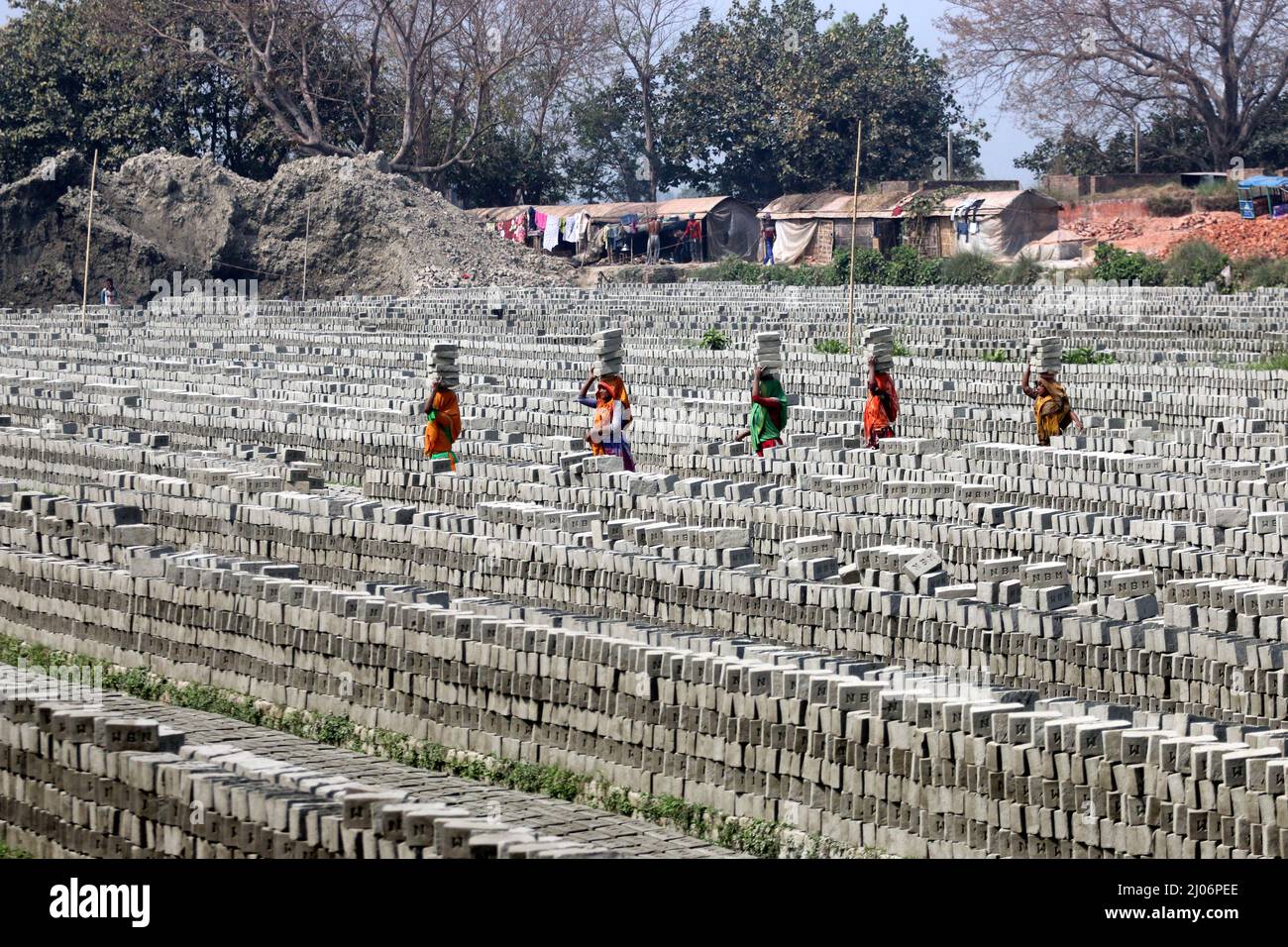 Workers transport bricks on their heads at a brick factory. Due to the high demand for bricks due to the accelerated urbanization in Bangladesh, the b Stock Photo