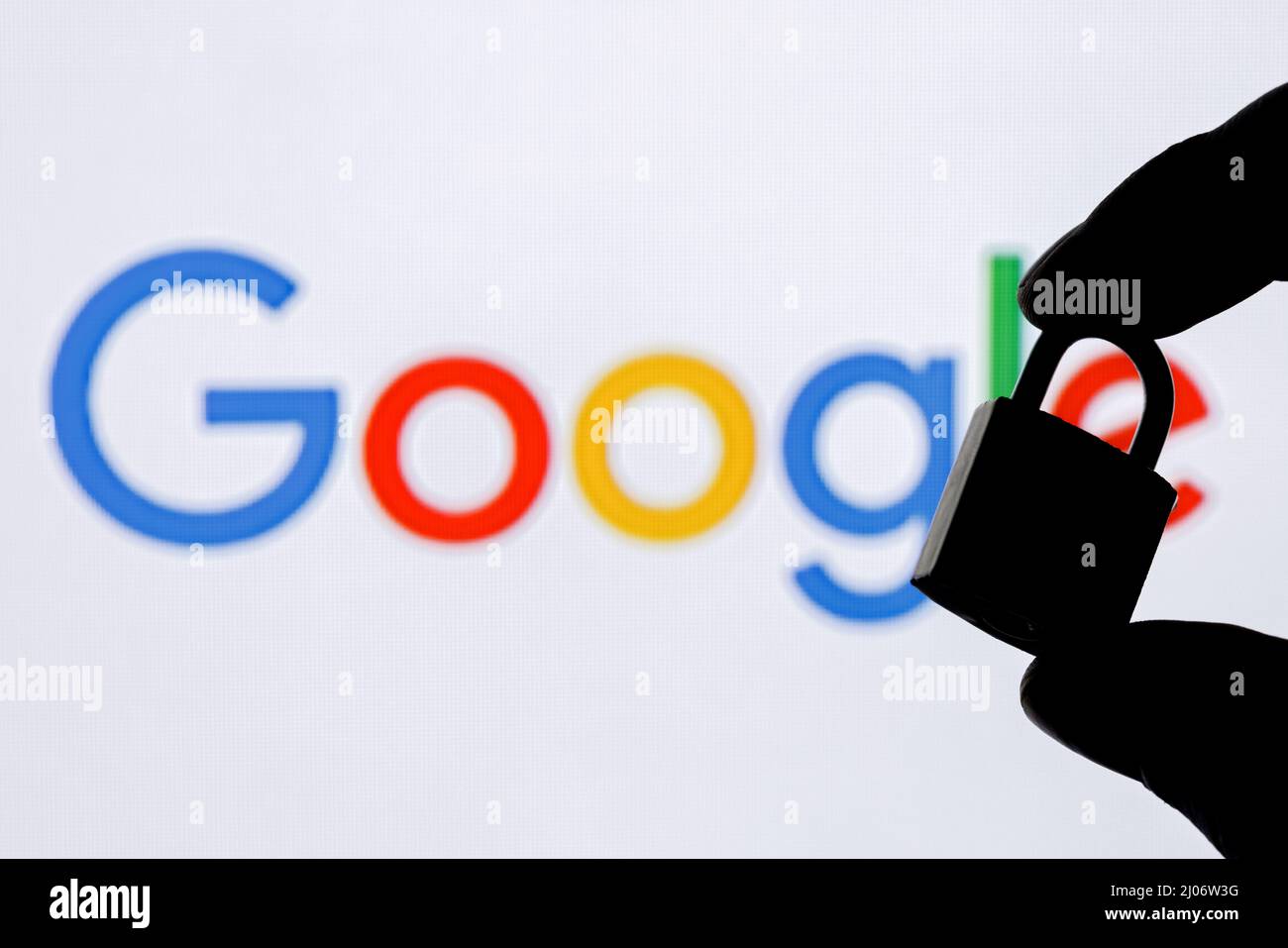 Fingers hold a closed security lock on the background of the Google technology company logo. The concept of data security in Google. Stock Photo