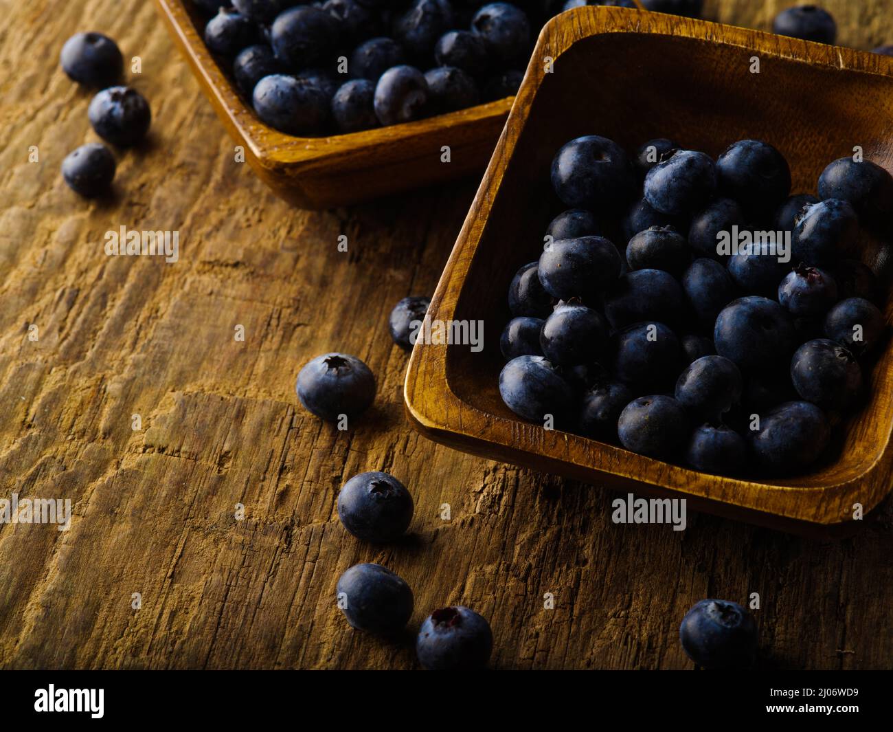 Fresh blueberries in bowls and in bulk on a wooden table. Rich harvest