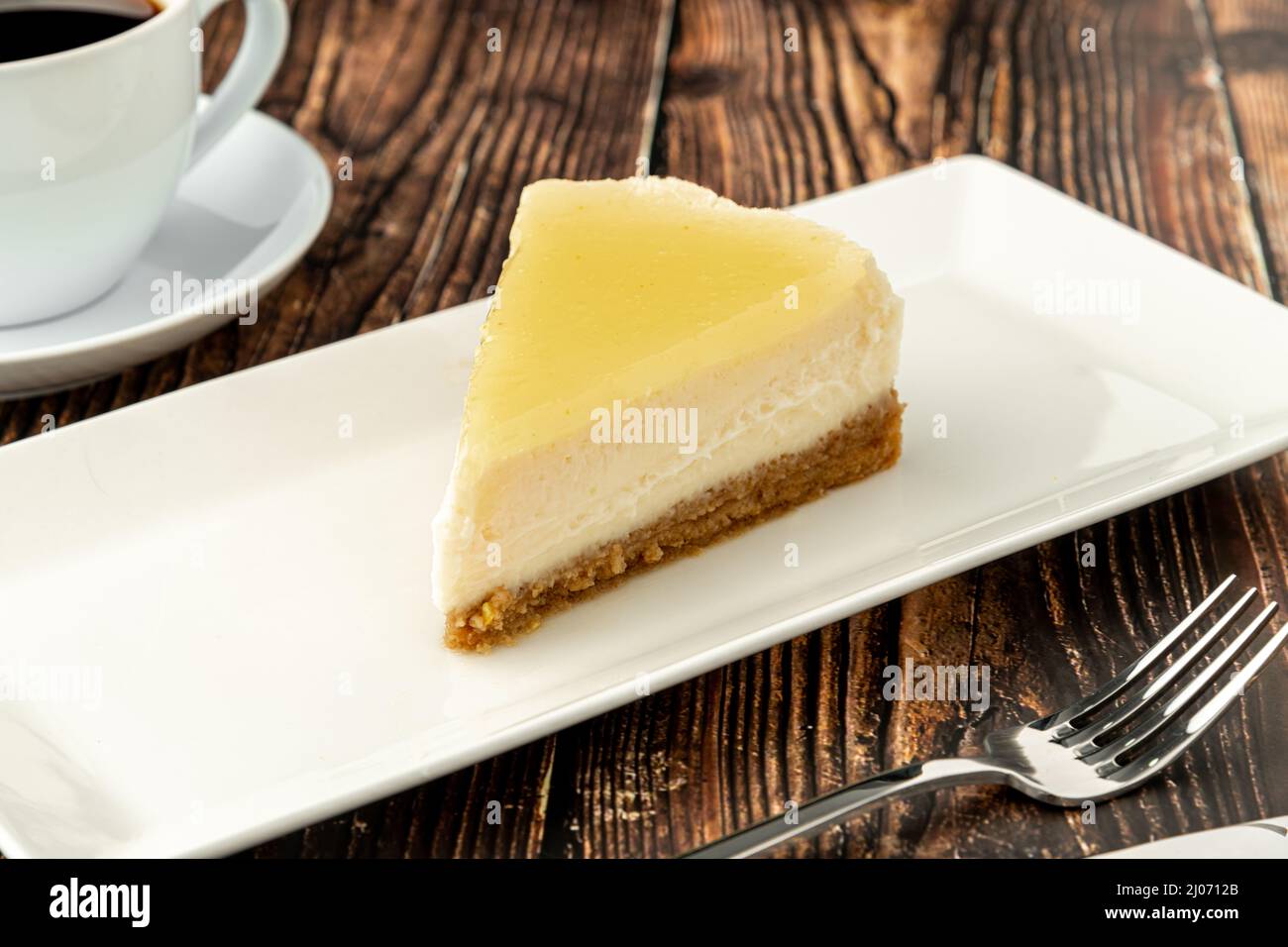 Delicious lemon cheesecake served with coffee on wooden table Stock Photo