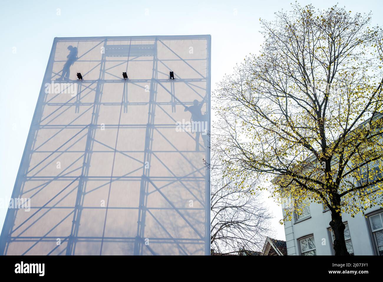 Dordrecht, Netherlands - April 15, 2019: Shadows and silhouettes on white canvas sheet in The Passion. Workmen constructing the scaffolding of tempora Stock Photo