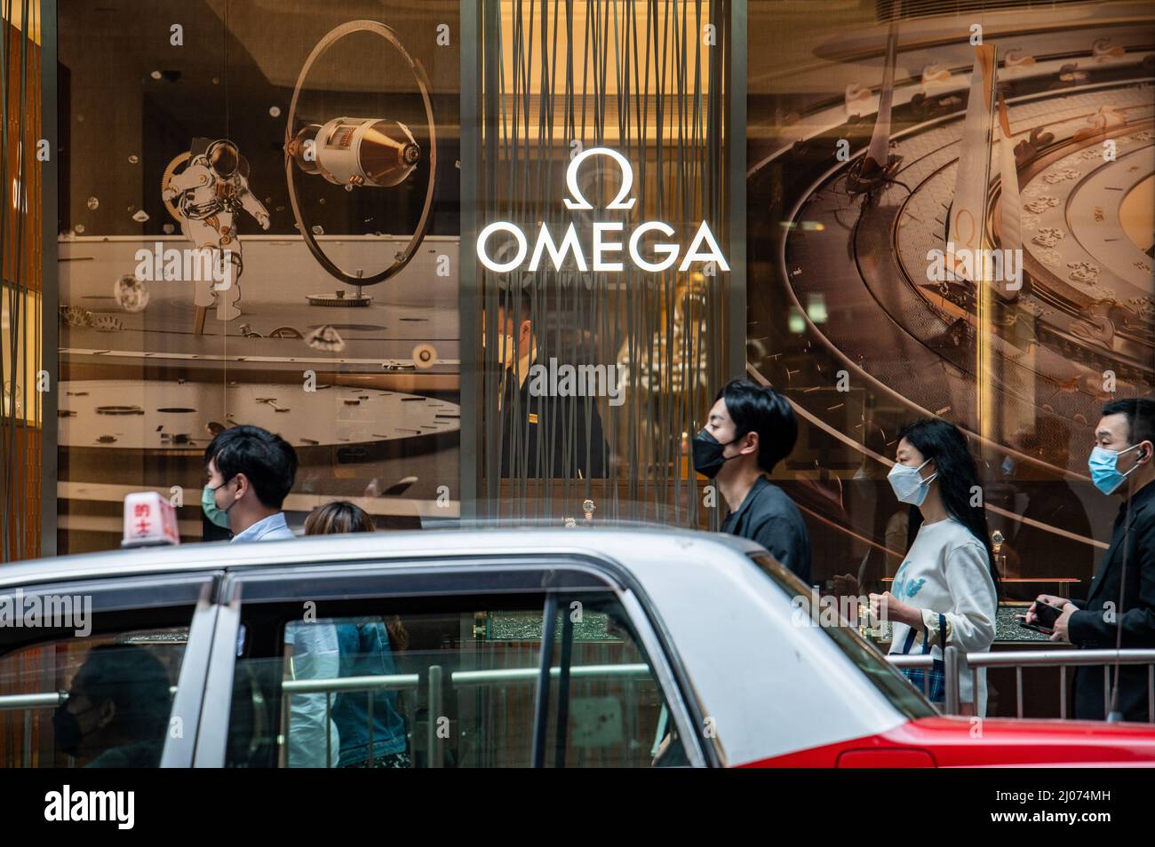 Shoppers wearing surgical masks walk by an Omega store in the Central