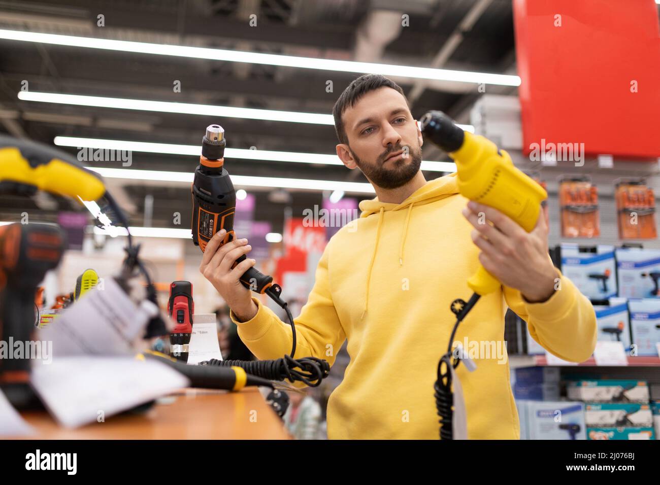 man chooses a new electric drill in power tool shop Stock Photo Alamy
