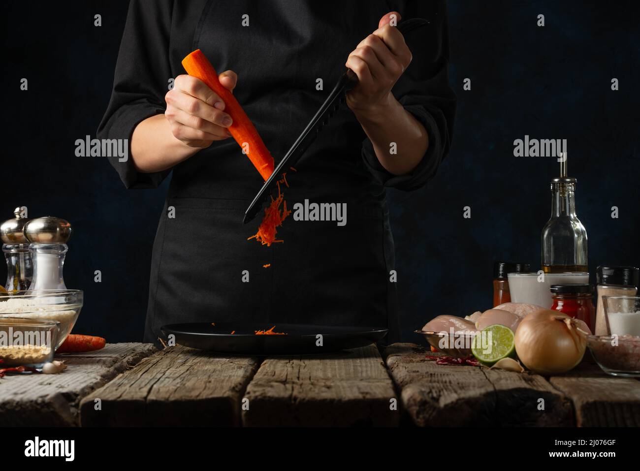 https://c8.alamy.com/comp/2J076GF/professional-chef-grates-carrot-on-the-plate-backstage-of-cooking-traditional-indian-chicken-curry-on-dark-blue-background-frozen-motion-concept-of-2J076GF.jpg