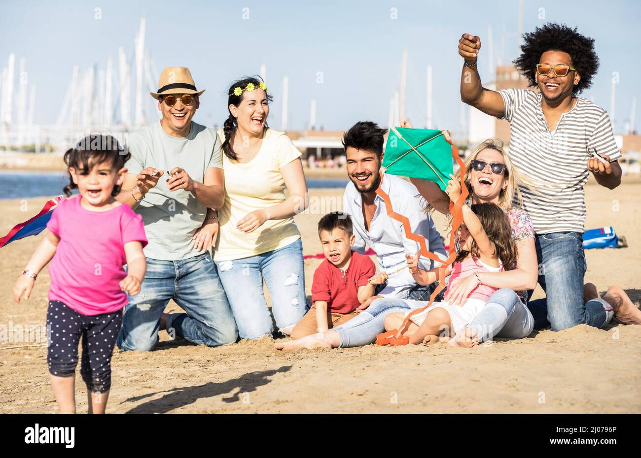 Happy multiracial families and children playing together with kite at beach vacation