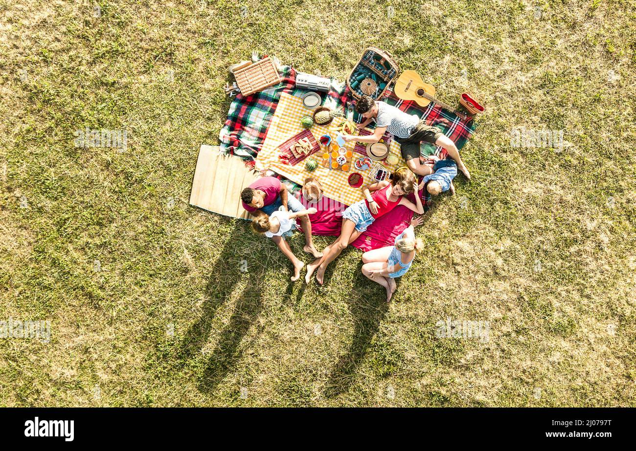 Aerial drone view of happy families having fun with kids at picnic barbecue party - Multiracial happiness and love concept with mixed race people play Stock Photo