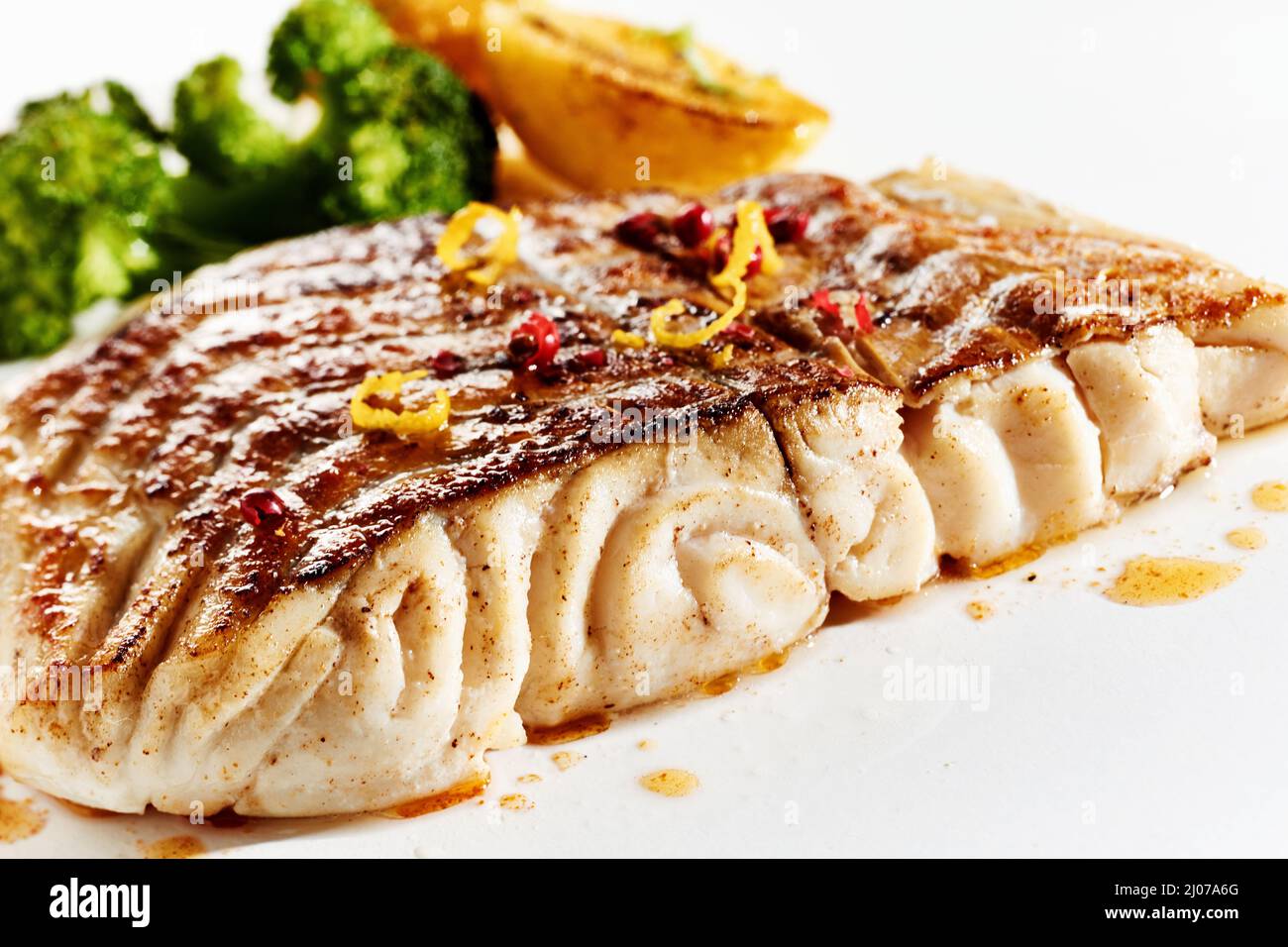 Closeup of nutritious grilled fish fillet and vegetables served on white background for lunch Stock Photo