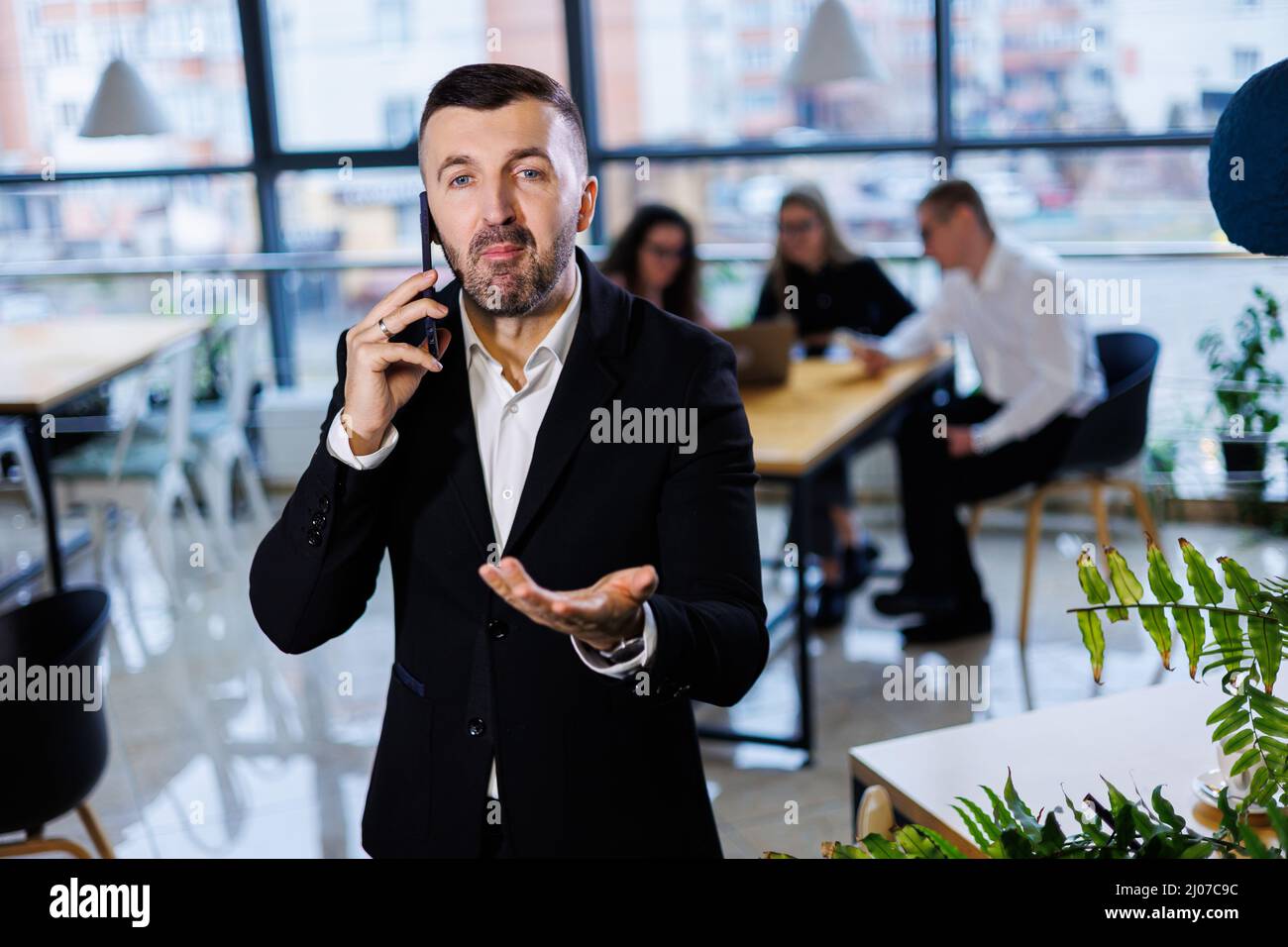 Handsome young businessman in modern suit using his mobile phone ...