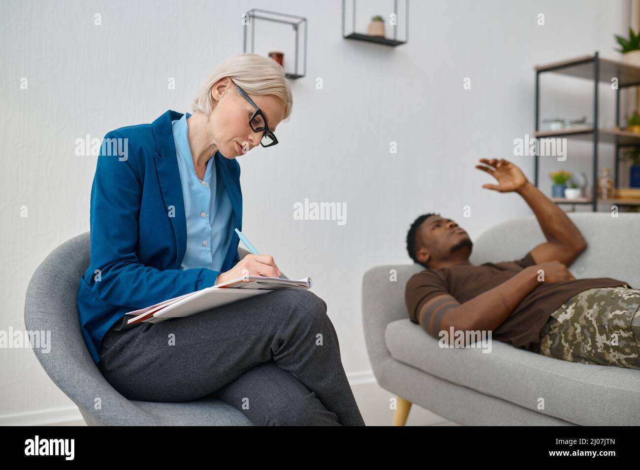 Psychologist making notes while male soldier talking Stock Photo