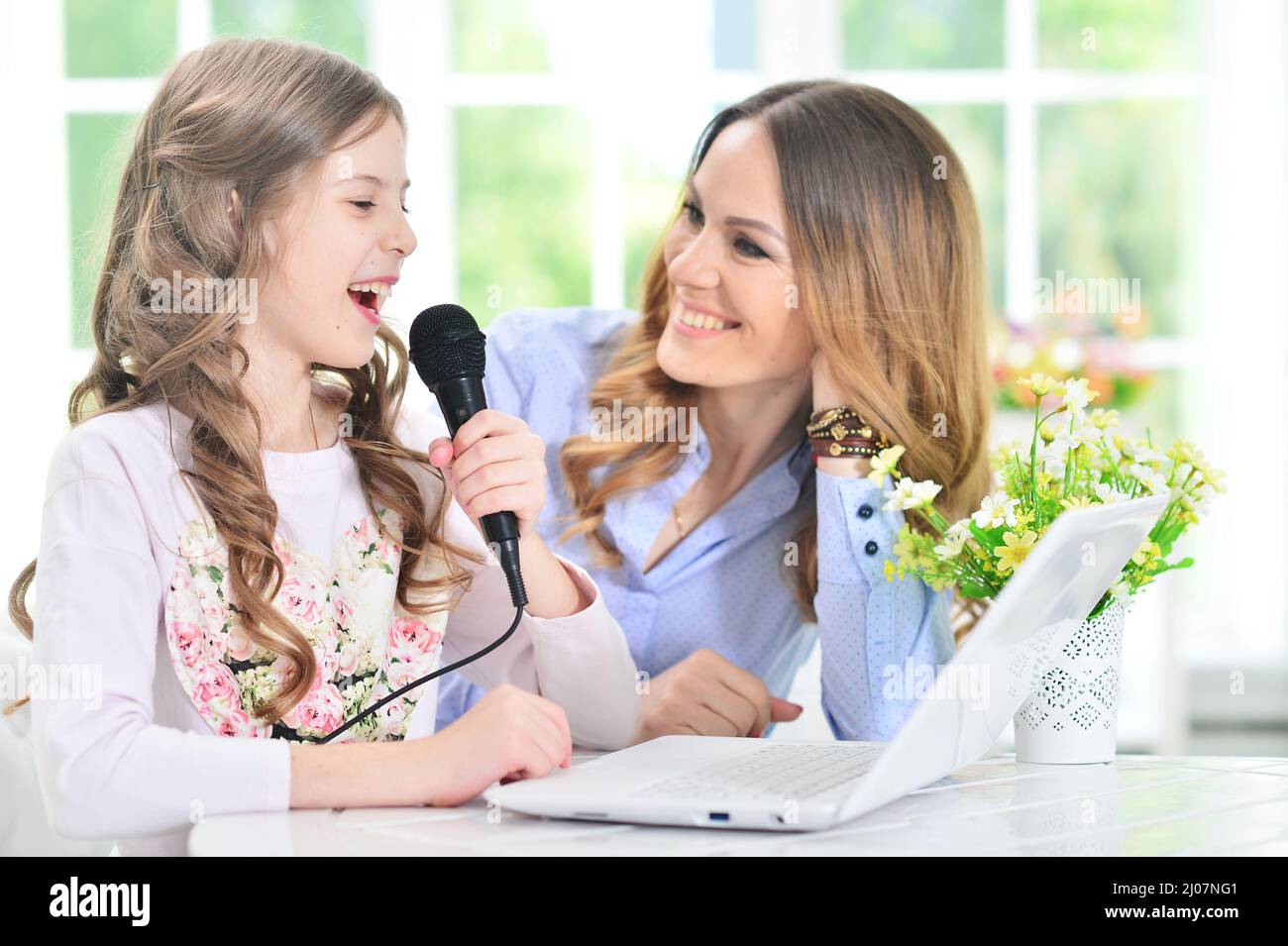 Mother and daughter with laptop computer singing karaoke Stock Photo