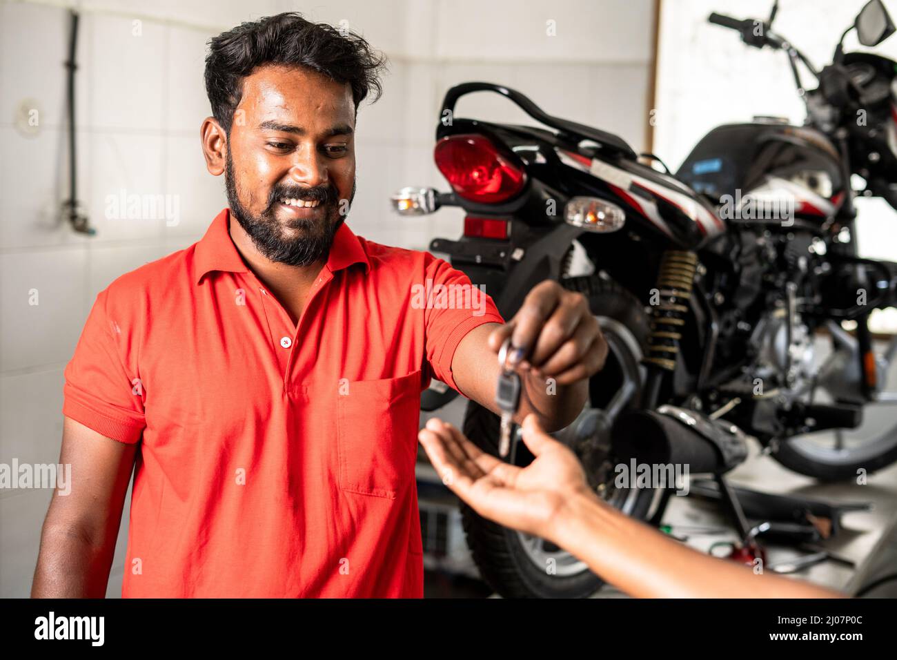 smiling motorbike mechanic giving motobike keys to customer after