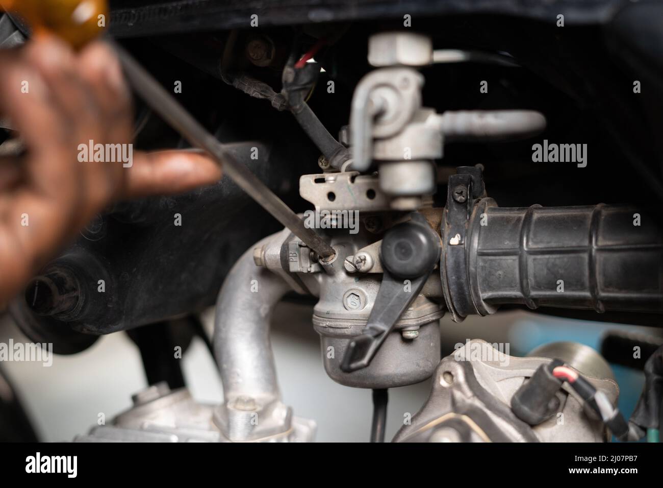 Close up shot of mechanic busy fixing motorbike air filter at garage - concept of repair and maintenance service. Stock Photo