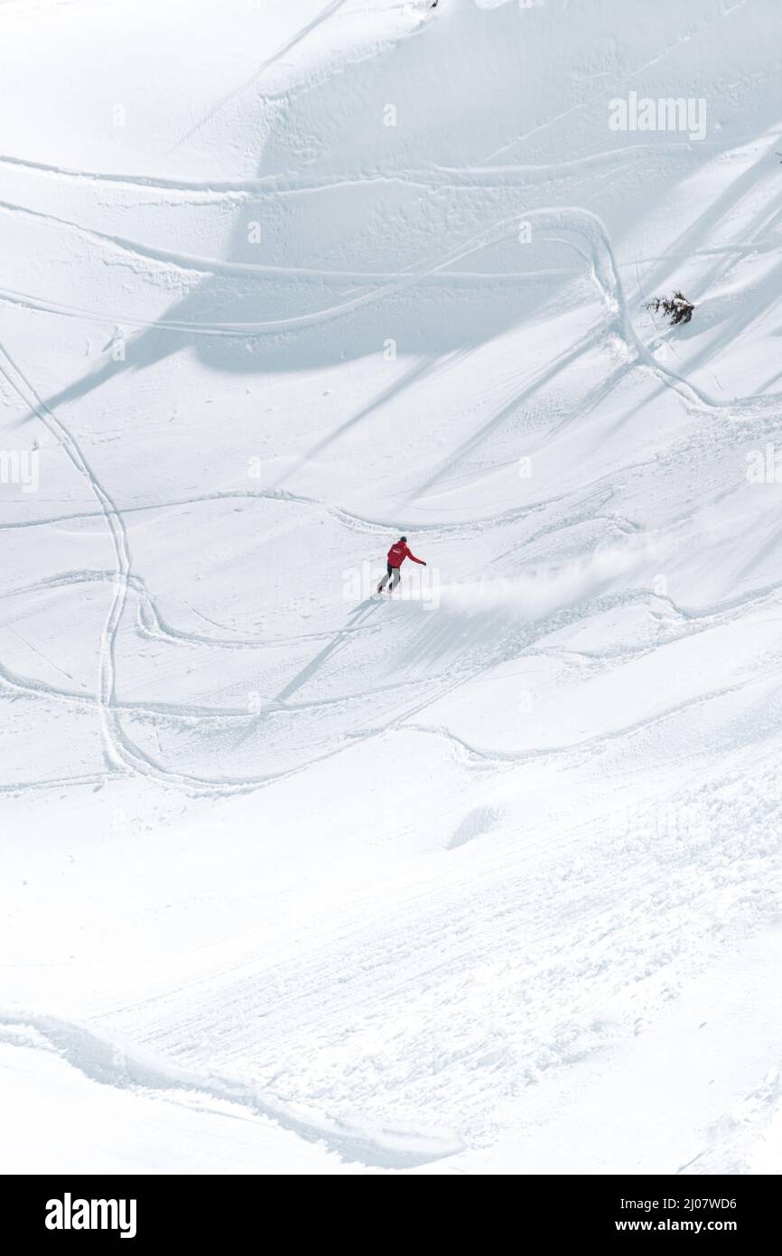Vertical shot of a skier sliding down a mountain in deep snow on a
