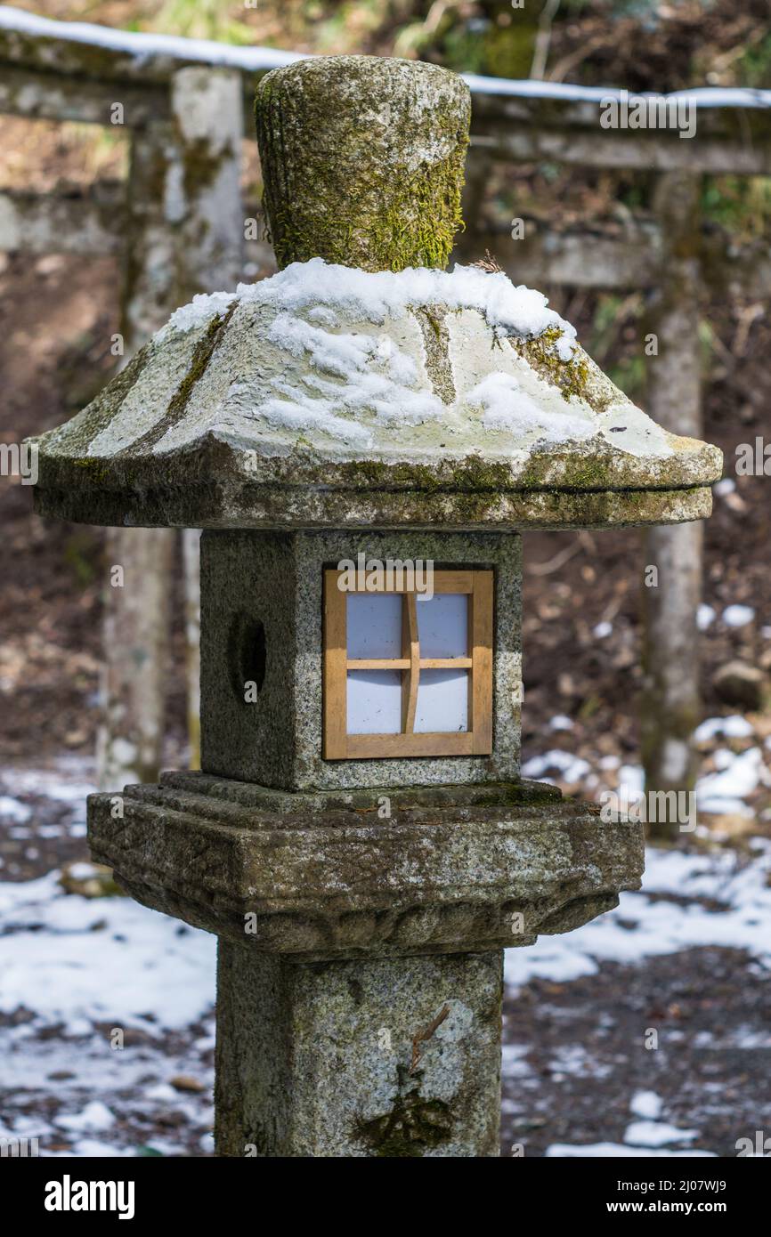 Traditional Japanese stone lantern covered in snow at Kurama-dera temple in Kyoto Japan Stock Photo