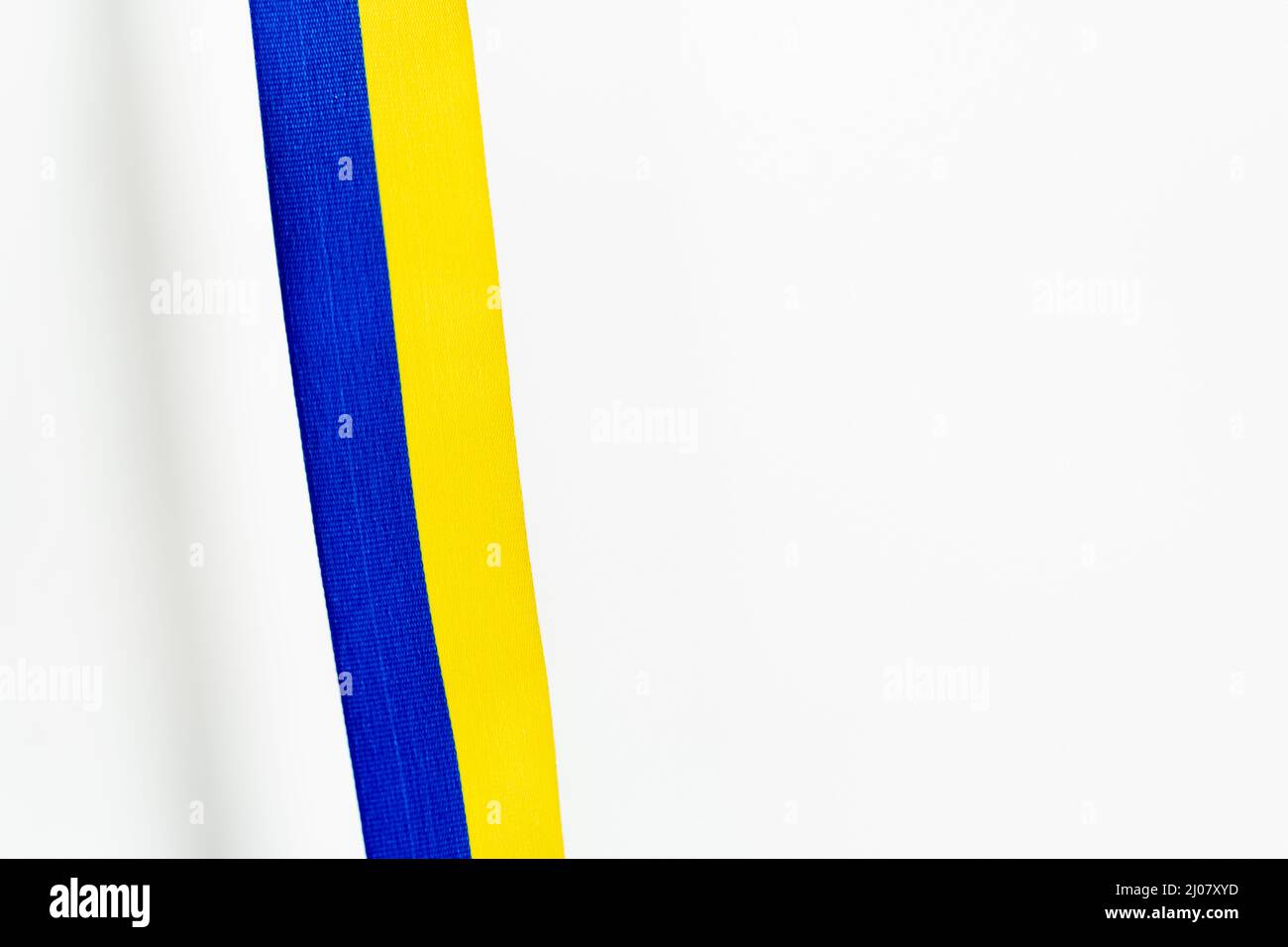 Top view of blue and yellow ribbon with shadow on white background