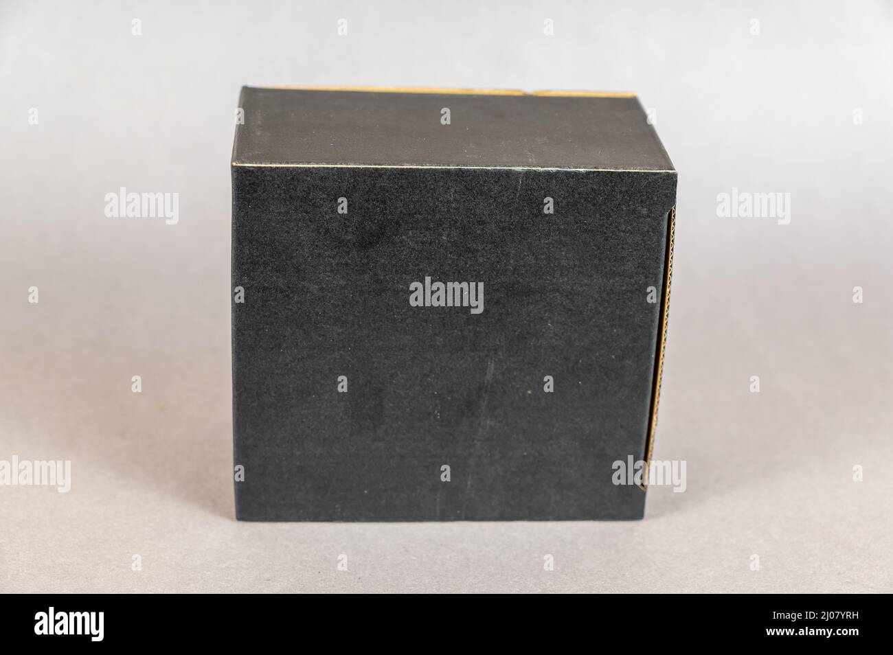 Rectangular black box on a gray background. Closed cardboard package with correct geometric shape. Stock Photo