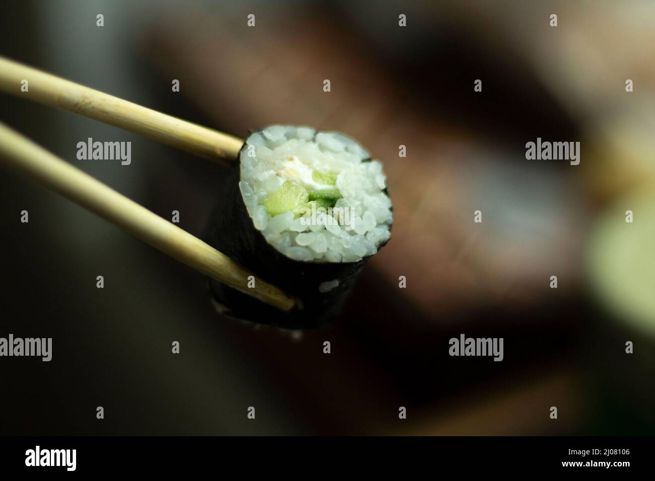 Sushi holds with sticks. Sushi with rice and cucumber. Asian cuisine. Fresh food. Stock Photo