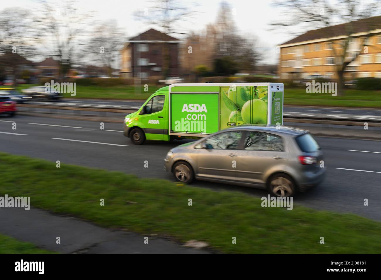 Asda online home food shopping delivery van driving along a busy road in panning shot with copy space. Stock Photo