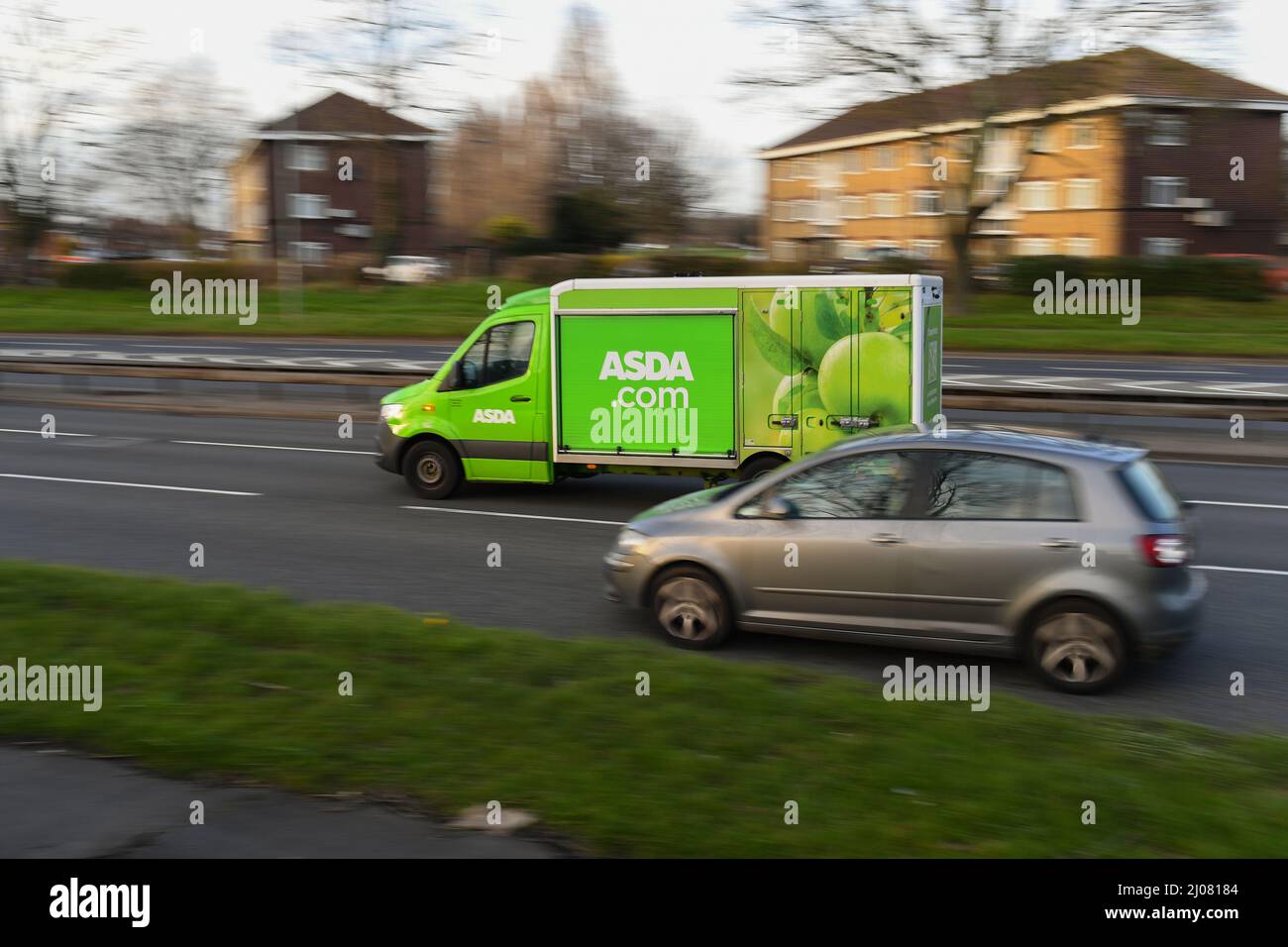 Asda online home food shopping delivery van driving along a busy road in panning shot with copy space. Stock Photo