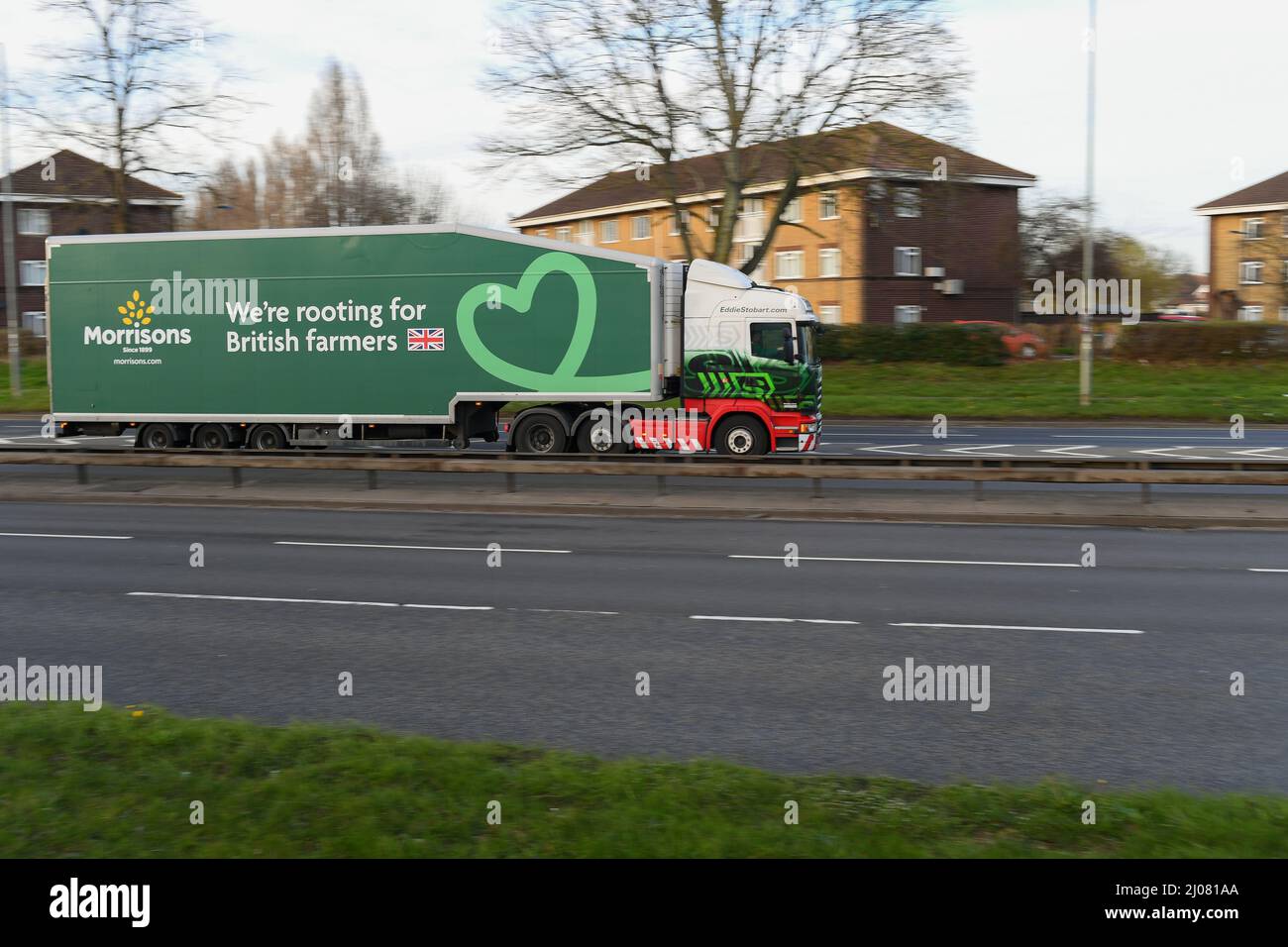 Morrisons supermarket articulated lorry driving along road with logo were rooting for British farmers on side of truck. Stock Photo