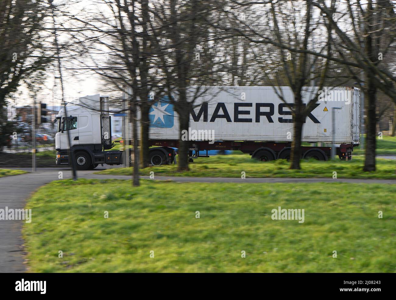 Maersk container lorry going into Southampton Container port panning through trees with copy space. Stock Photo
