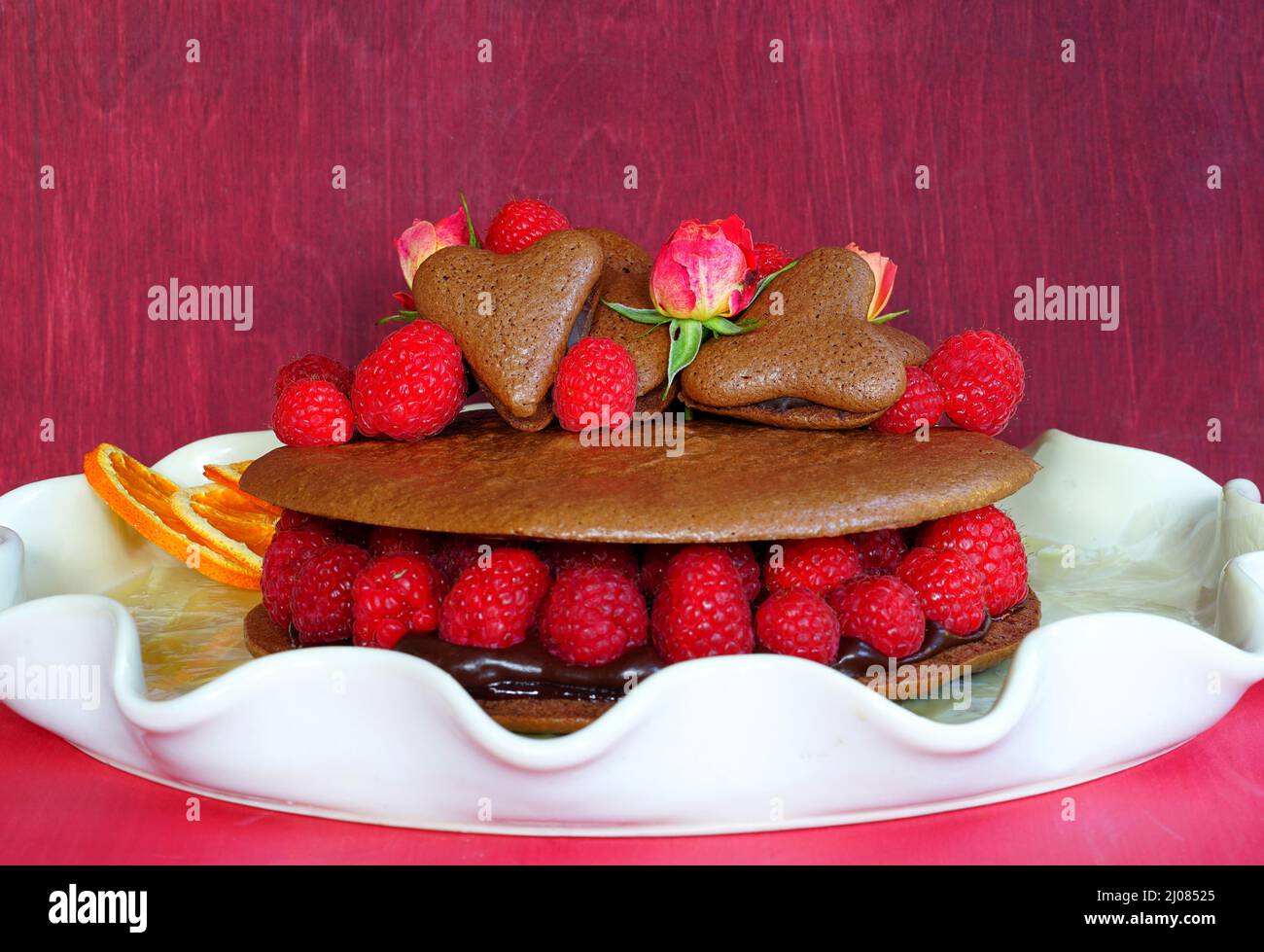 A giant chocolate macaron cake with fresh raspberries and rose flowers Stock Photo