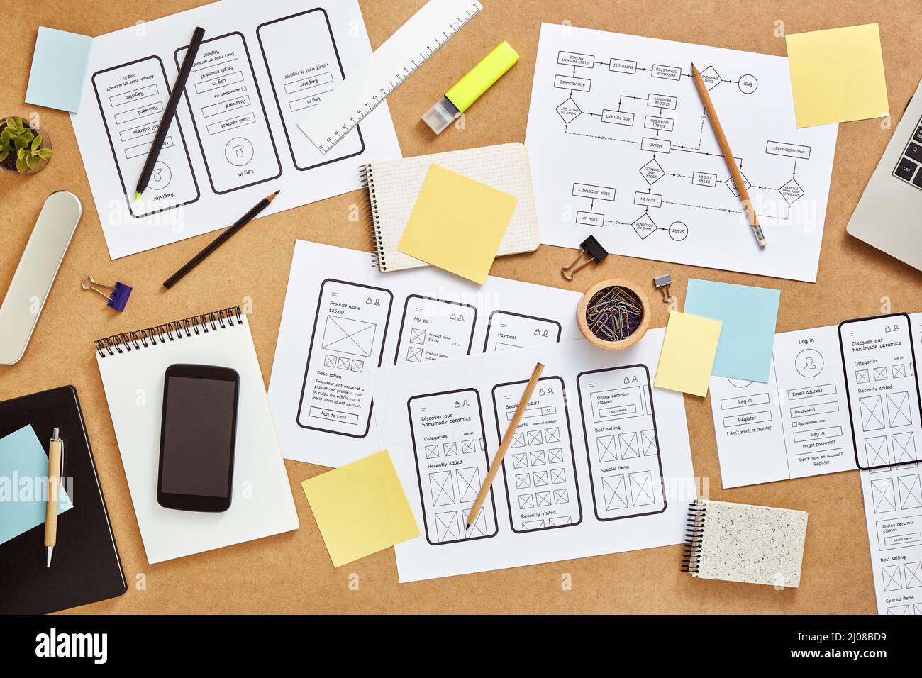 Top view image of busy web UX designers workspace with many mobile app wireframe sketches and user flow. Stock Photo