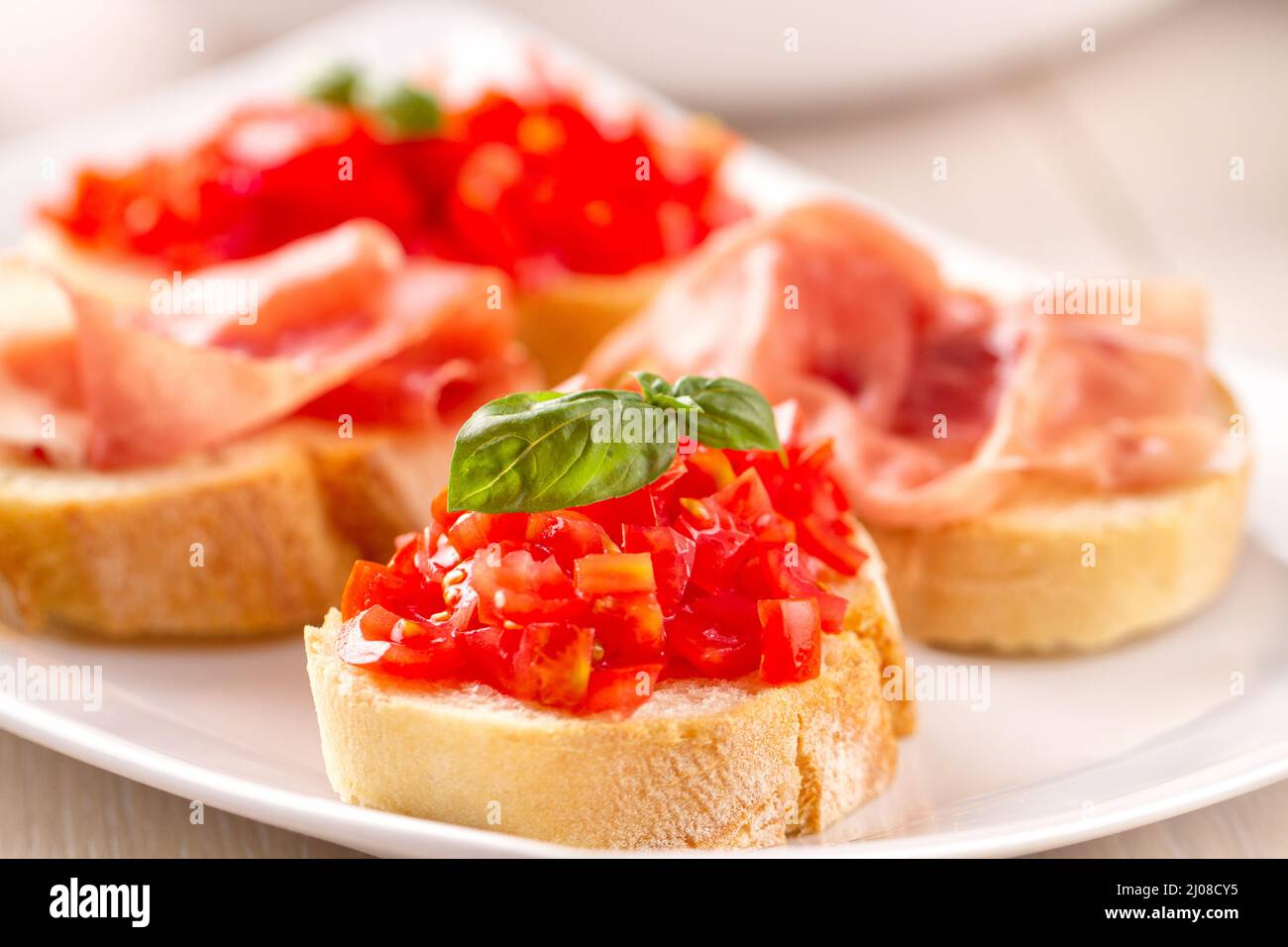 Italian appetizer bruschetta with Parma ham and fresh tomatoes on a plate Stock Photo