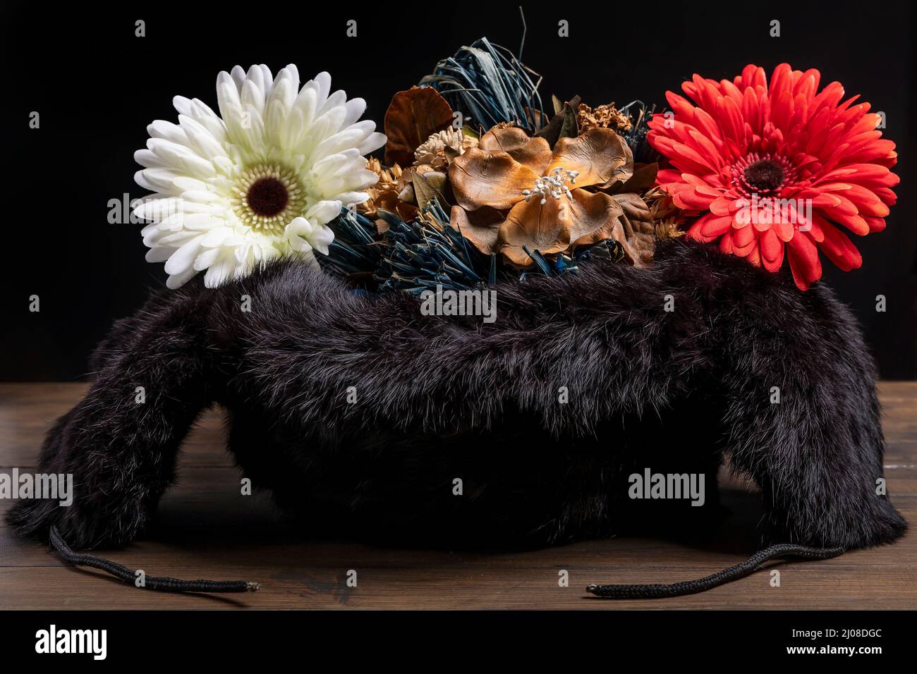 An inverted Russian ushanka hat contains dried, fake flowers, as a symbol of peace and love Stock Photo
