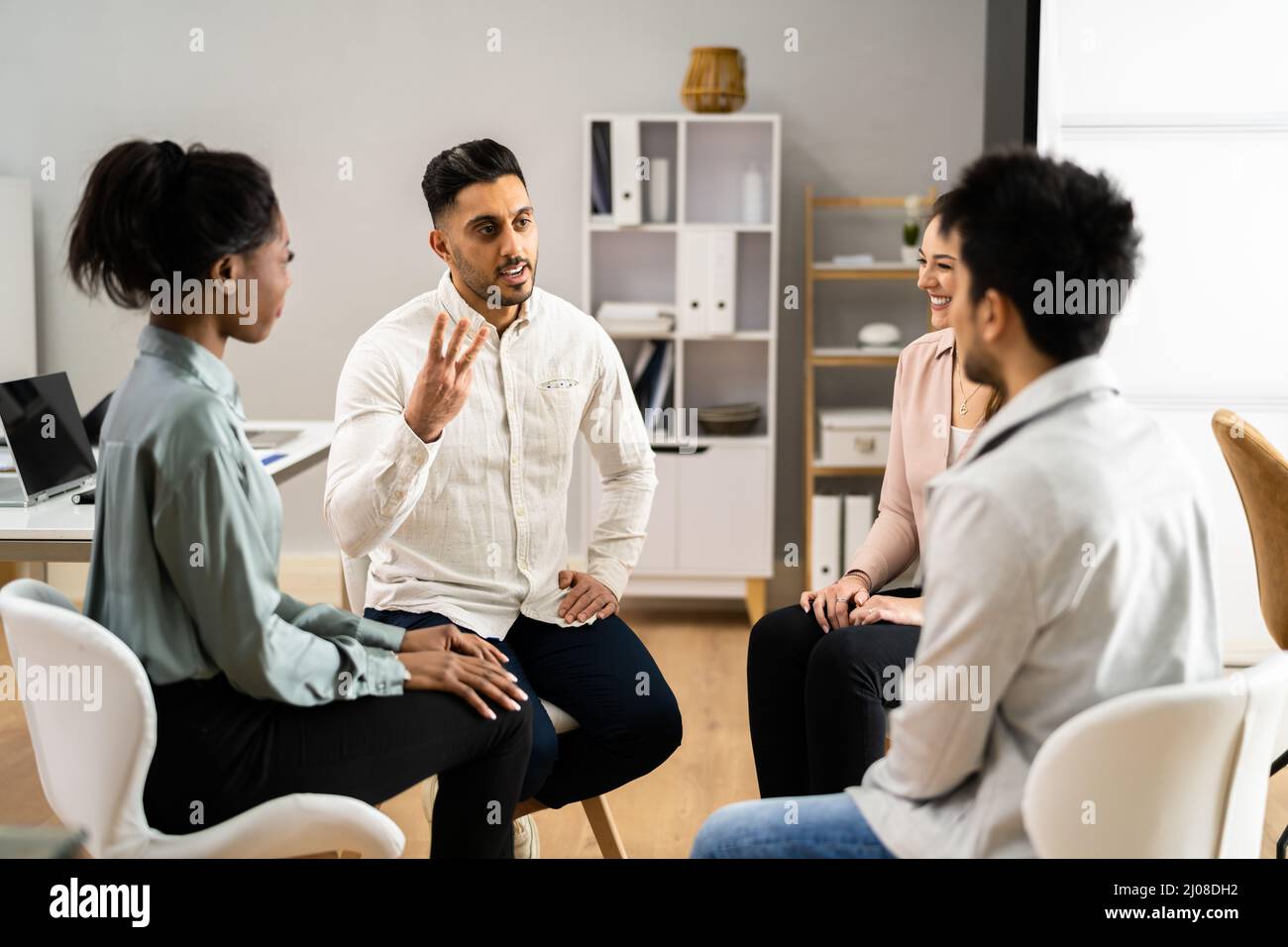 Two People Consoling Young Man During Group Therapy Session Stock Photo