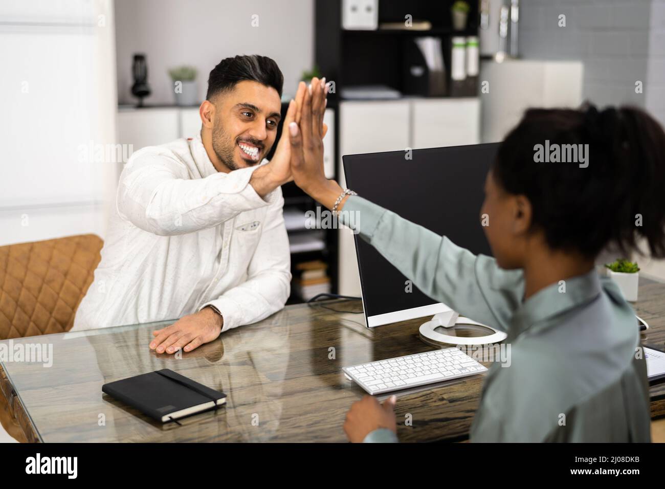 Businessman And Businesswoman Sitting On Chair Giving High Five In ...